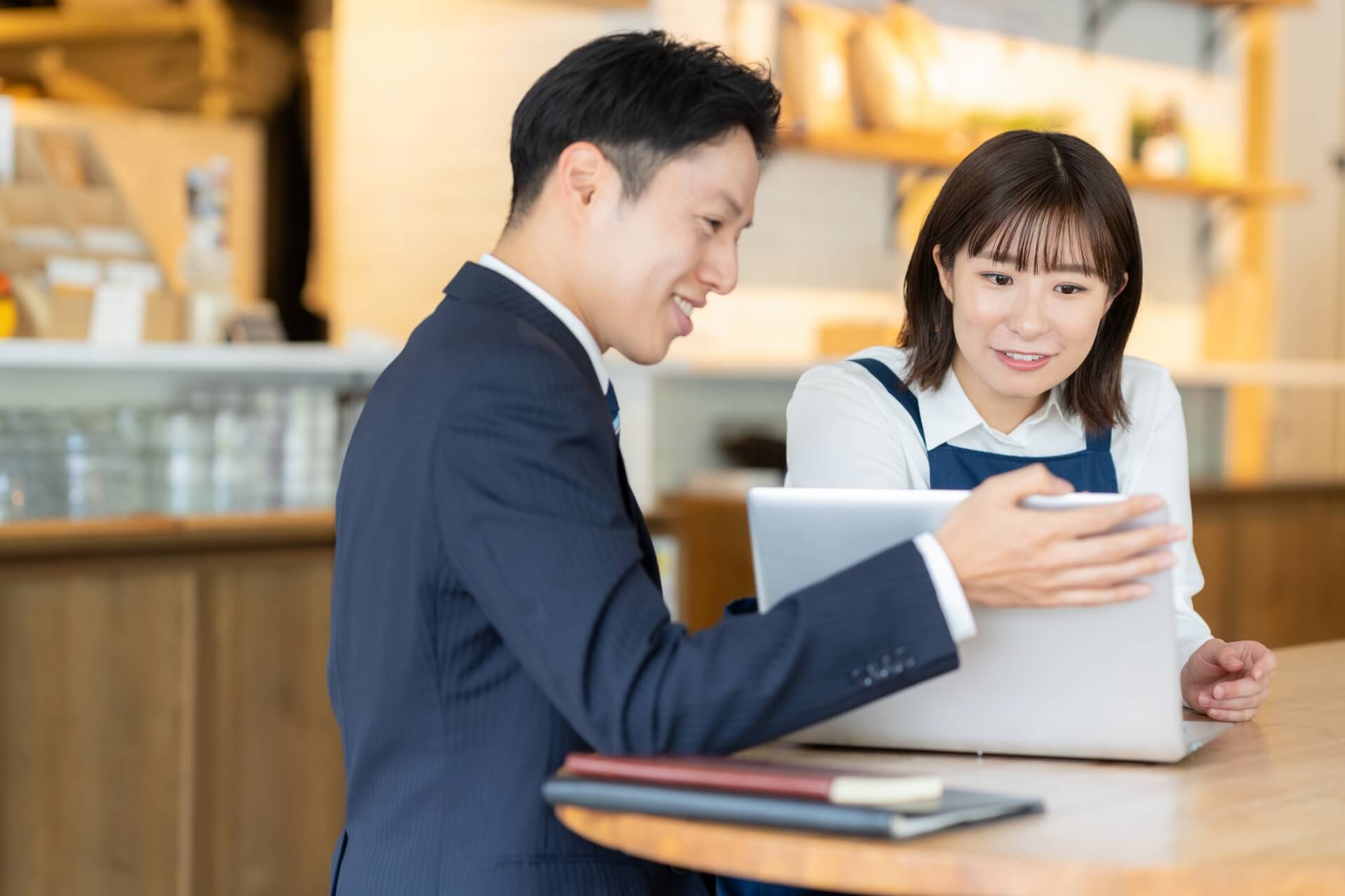 カフェでノートパソコンを使用する若い男女